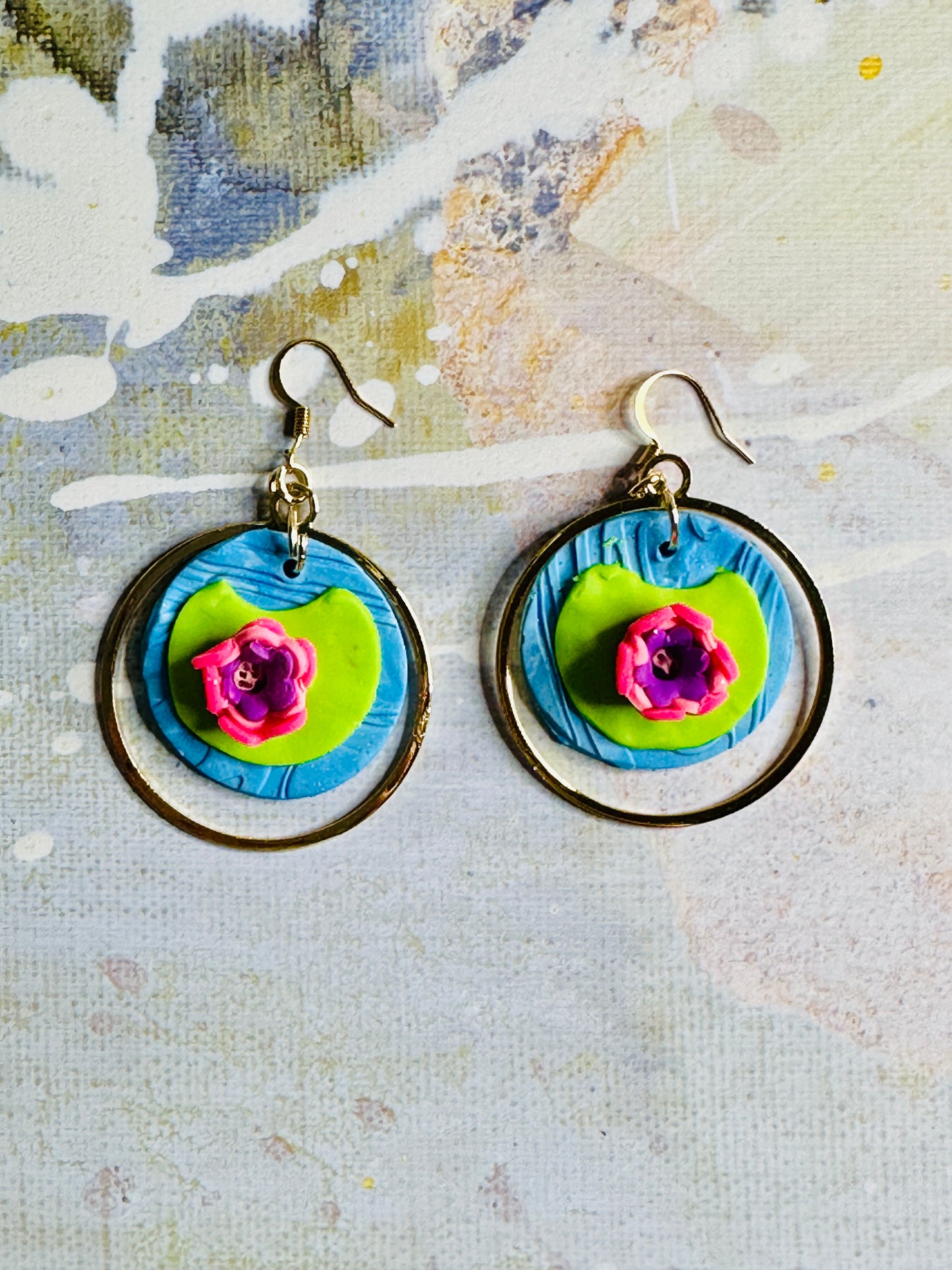 A pair of Monet Water Lily earrings on a colorful and abstract background.