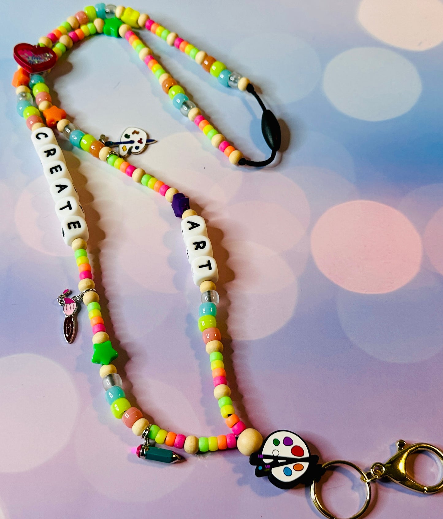 Beads on the lanyard that spell CREATE ART.