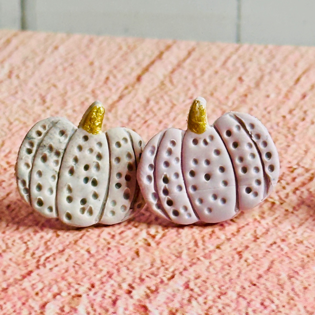A close up of the purple pumpkin stud earrings.  The texture of the pumpkin and the gold stem are in focus.